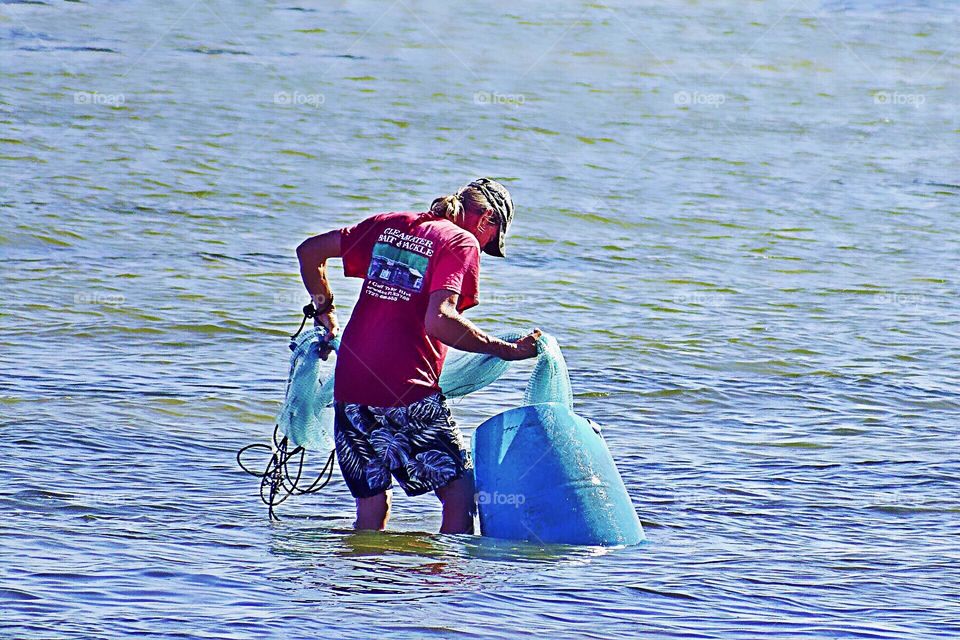 Fisherman using his nets in the bright blue water of the Gulf.