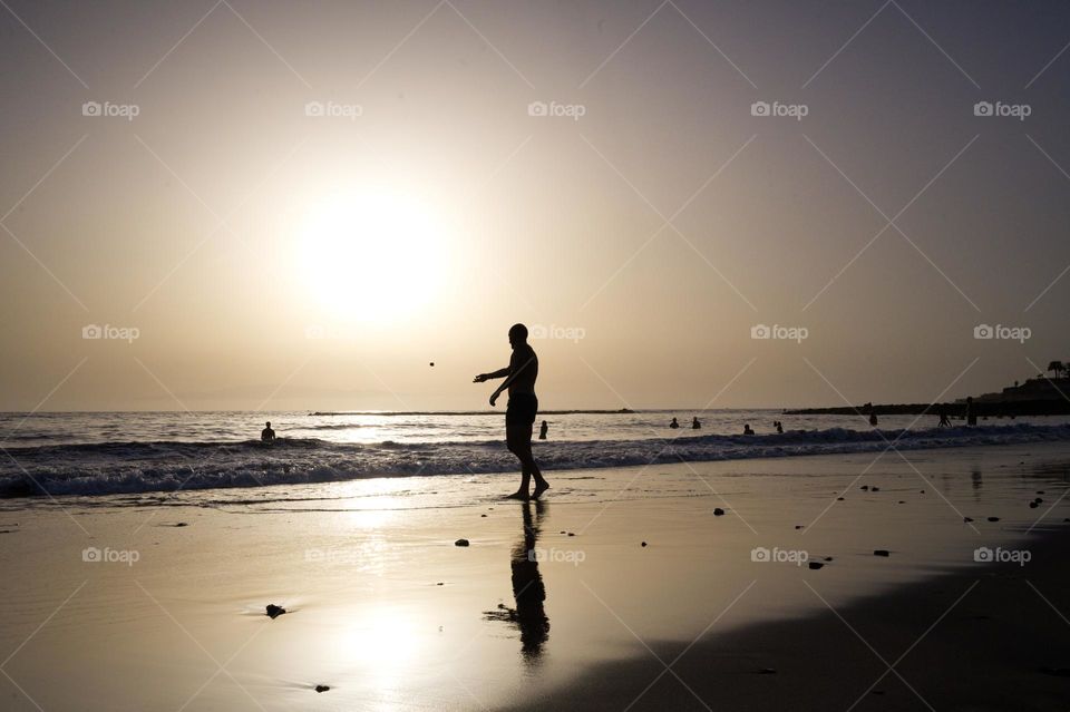 silhouette of man throwing a stone at the sea