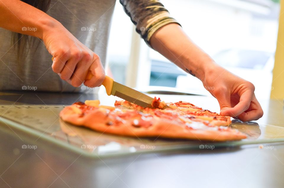 Person slicing pizza with knife