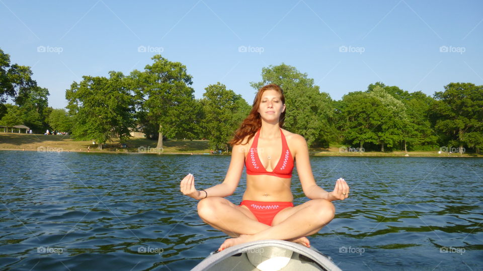 Woman doing yoga in front of lake at park