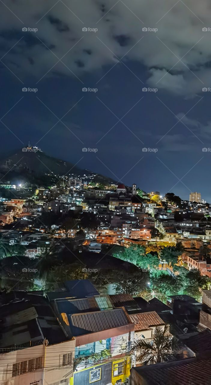 Night shot of Santiago de Cali, Colombia taken from a balcony in San Antonio, trees and buildings over the hill