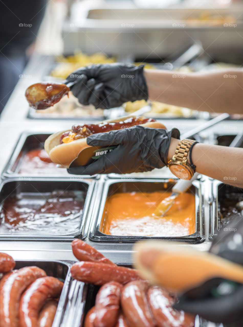 Chef's hands in gloves preparing hot dog on a fast food restaurant