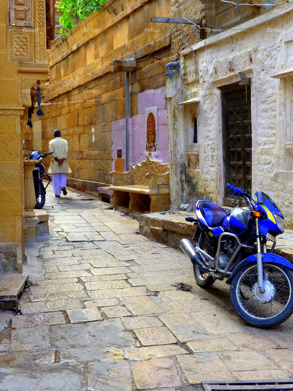 man walking in an indian town with blues motorcycle