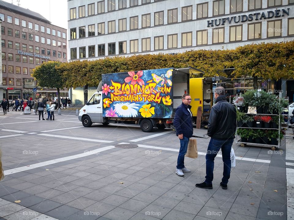 People selling flowers from a truck on the square.