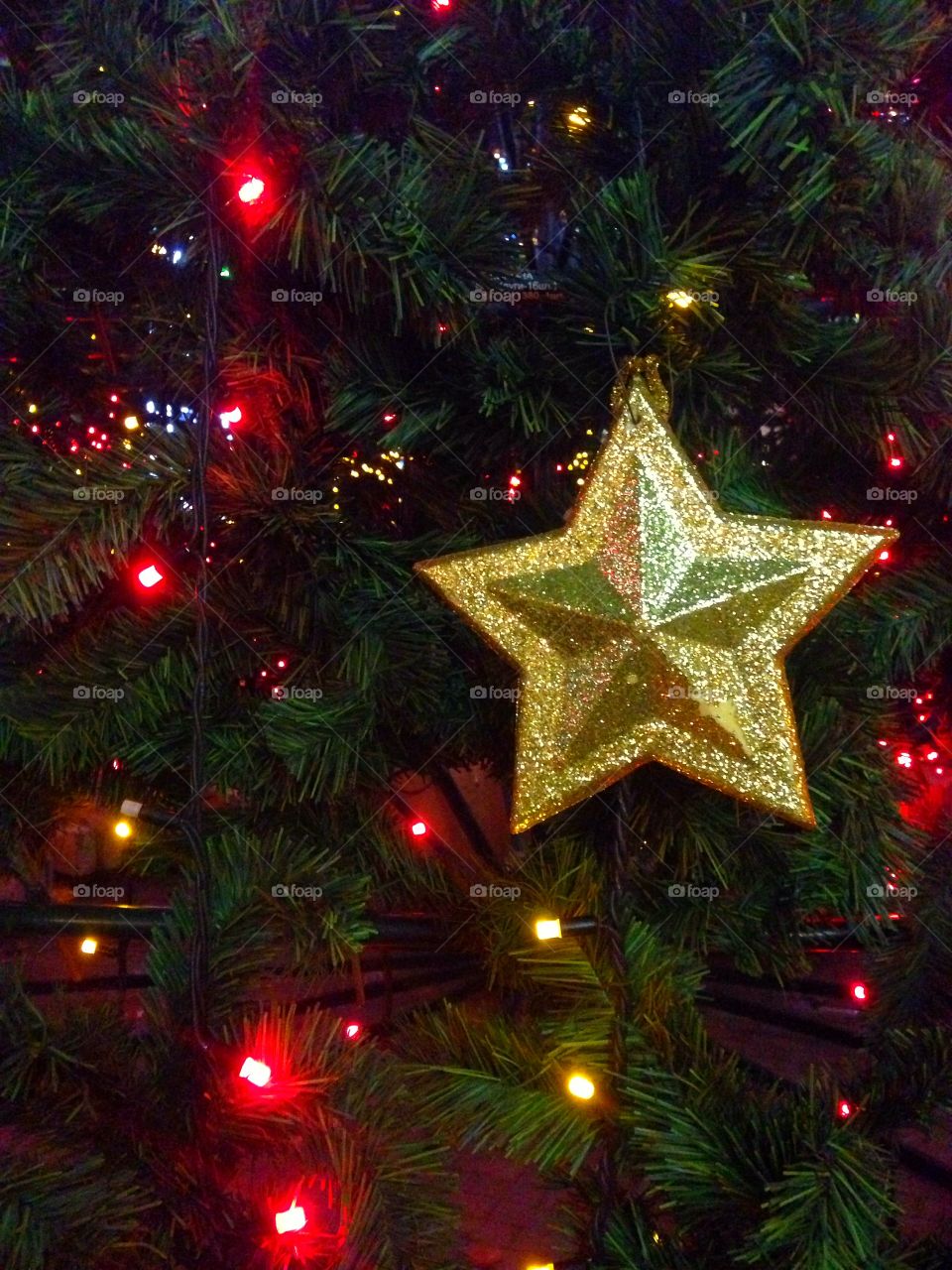 Gold plastic star, balls, red lights garland and other Christmas decorations on artificial fir tree in Moscow, Russia