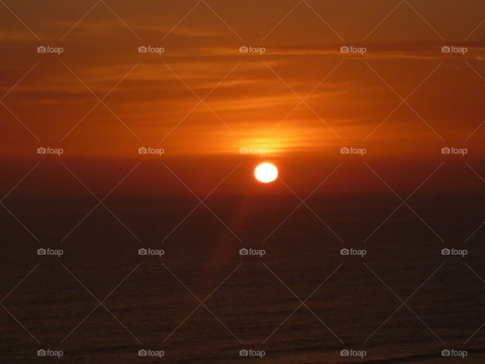 the sunset centered on the ocean in reddish and orange tones