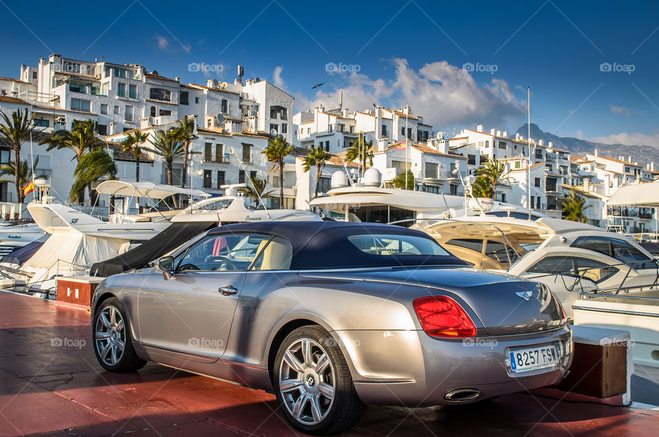 Bentley Convertible Parked next to Yachts . Luxury Bentley parked in Puerto Banus next to the big yachts 