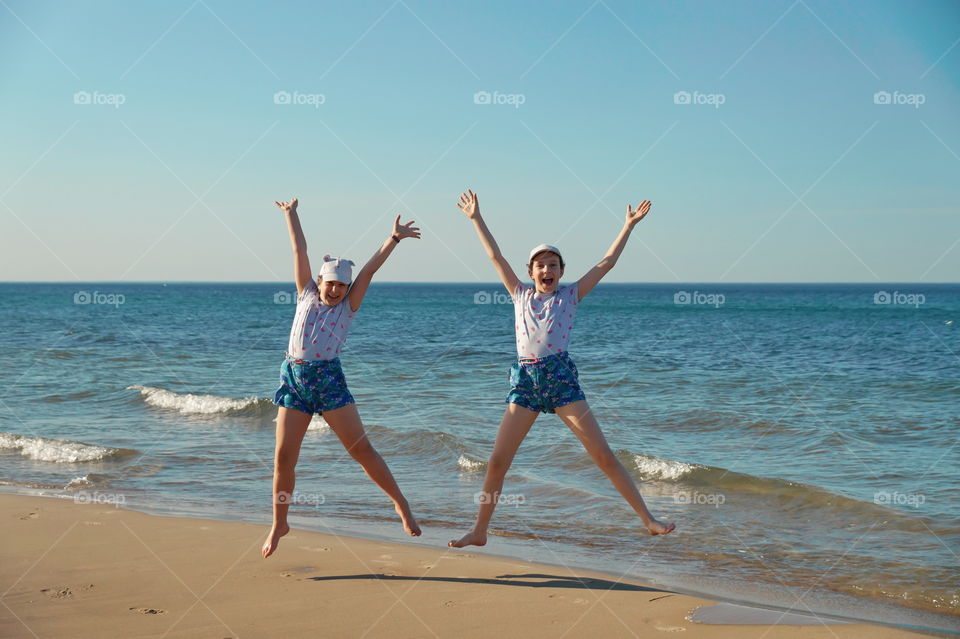 Two children jump for joy on the seashore