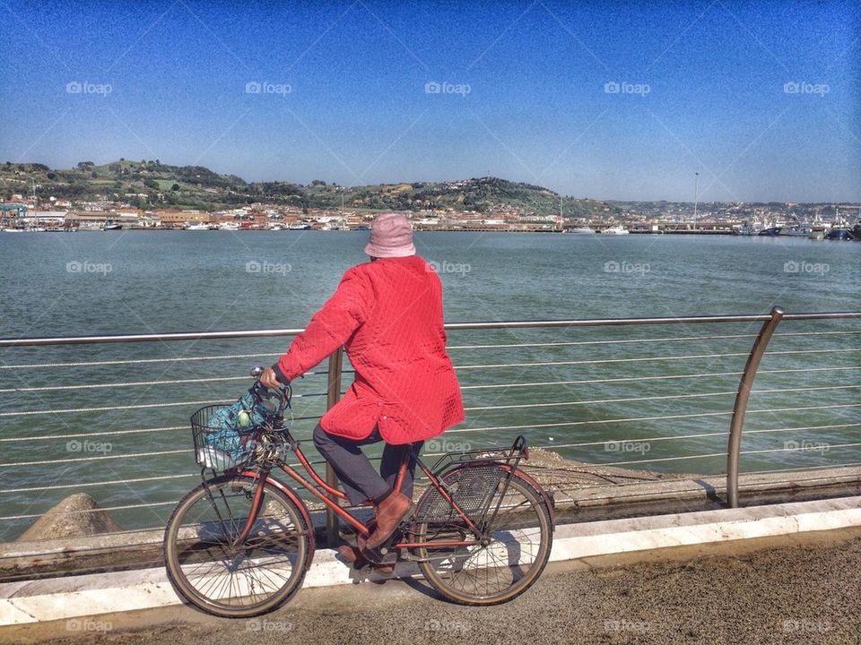 Old woman on her bicycle looking at San Benedetto del Tronto