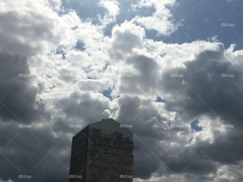 Clouds are surrounding a tall building 