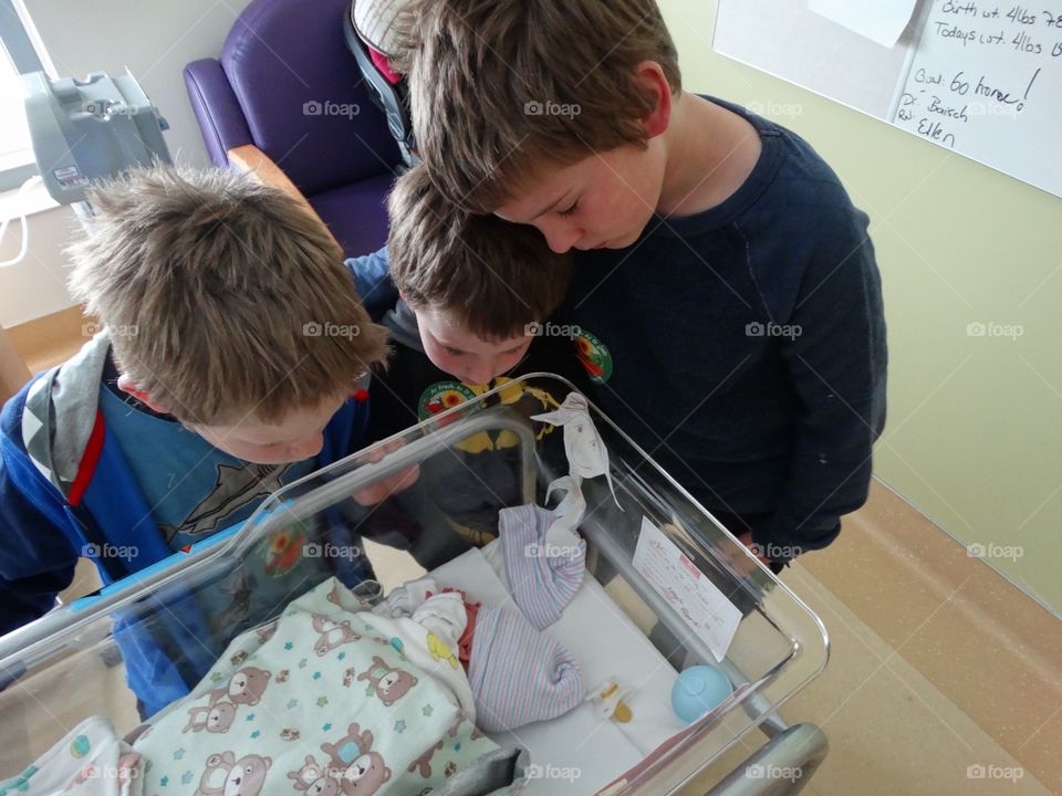 Brothers Gazing At Their Newborn Baby Sister
