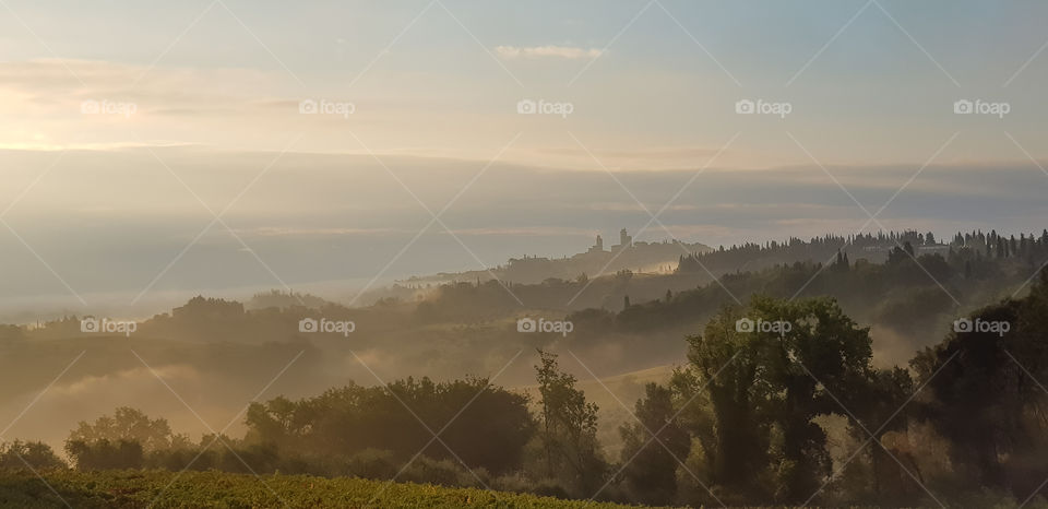 Misty morning in the Tuscan countryside with the towers of San Gimignano in the distance