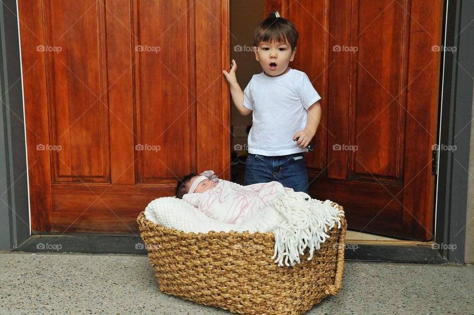 Surprised boy looking at baby sleeping in basket