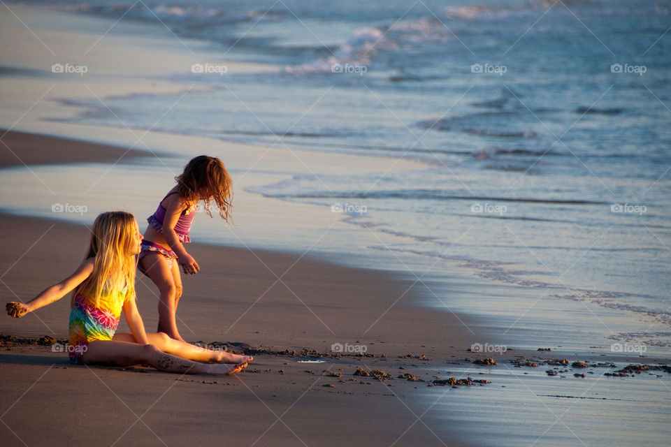 Two young girls playing in the sand on the California beach