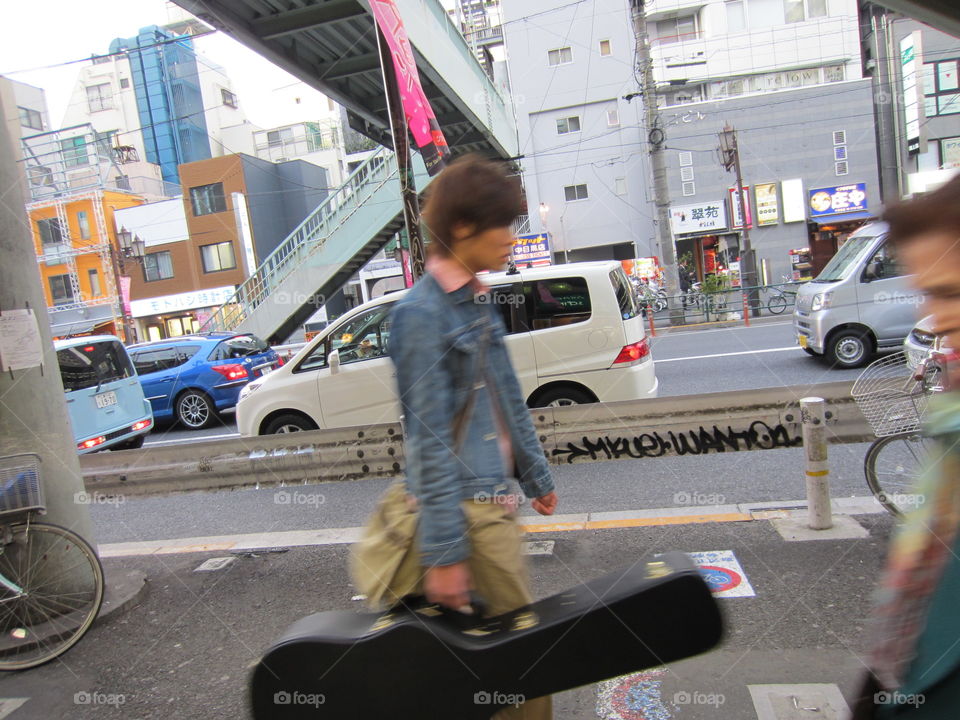 Nakameguro, Tokyo, Japan.  Young Musician Walking with his Guitar