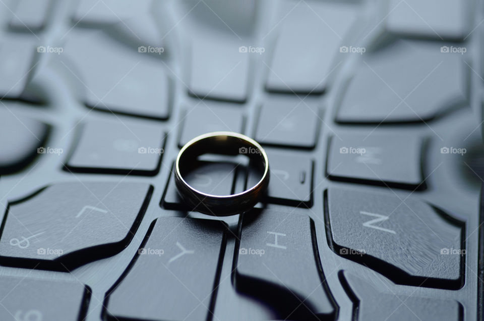 A digital effect featuring a four sided keyboard encircles a gold wedding band.