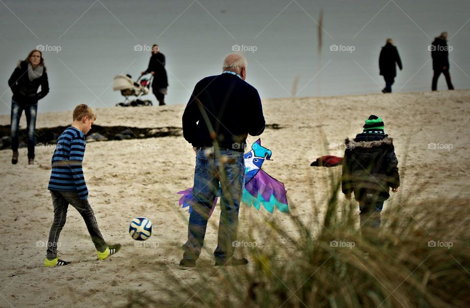 Grandfather plays with his grandchildren on the beach