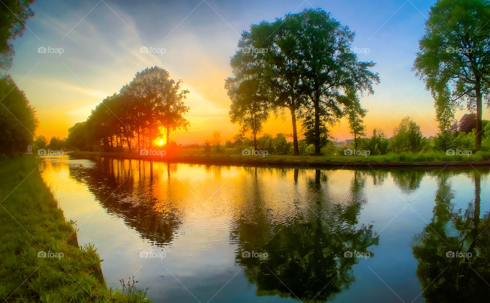 Glowing orange red sunset reflected in the water of the river