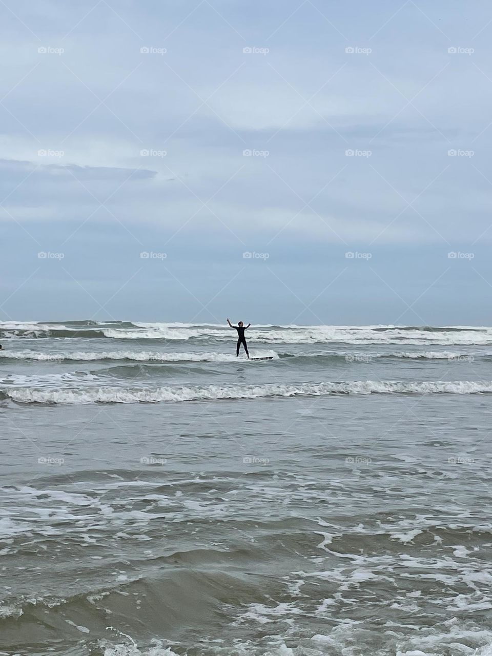 A person surfing with their arms up