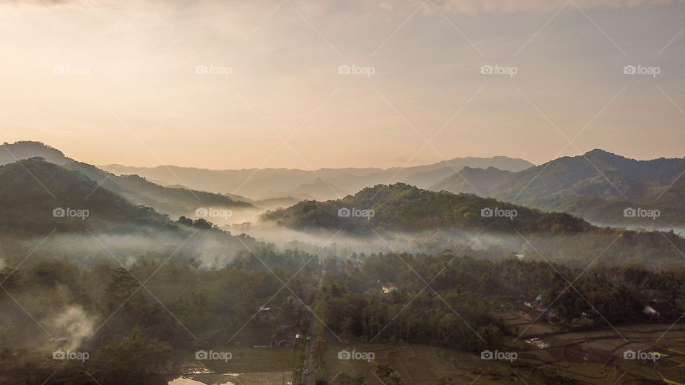 Magical golden hour aerial hidden village rice field, hills and mist purwerejo indonesia