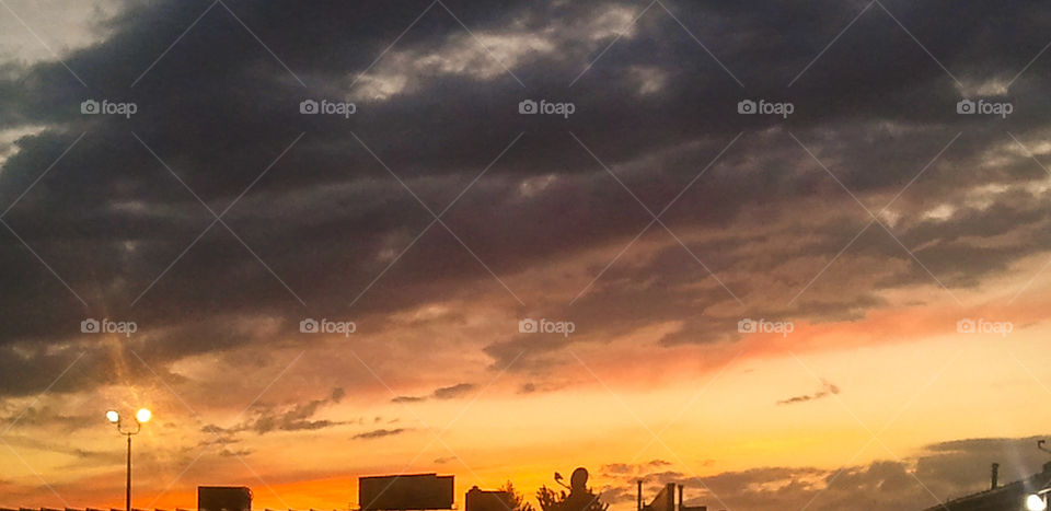 Clouds Bordering Fire. A cloudy sunset after a rainstorm. This photo had some work done on it using the phone app Photoshop Express.