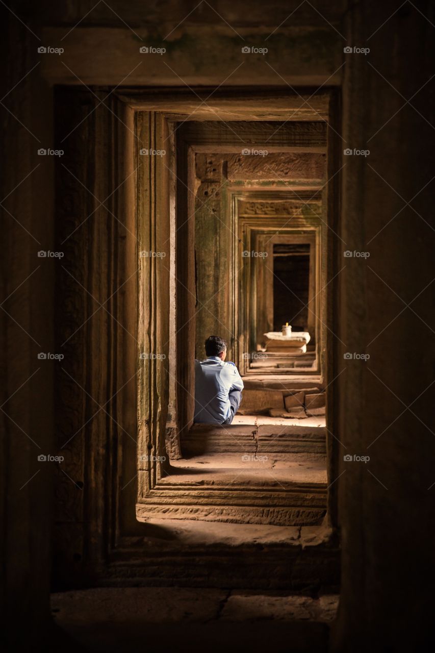 Man sitting in a temple (Angkor Wat), lost in thoughts 
