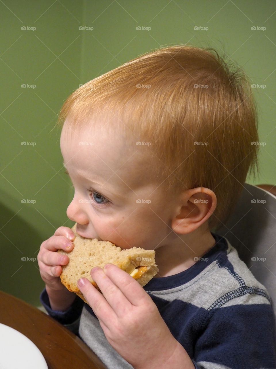 Toddler boy eating his peanut butter and banana sandwich