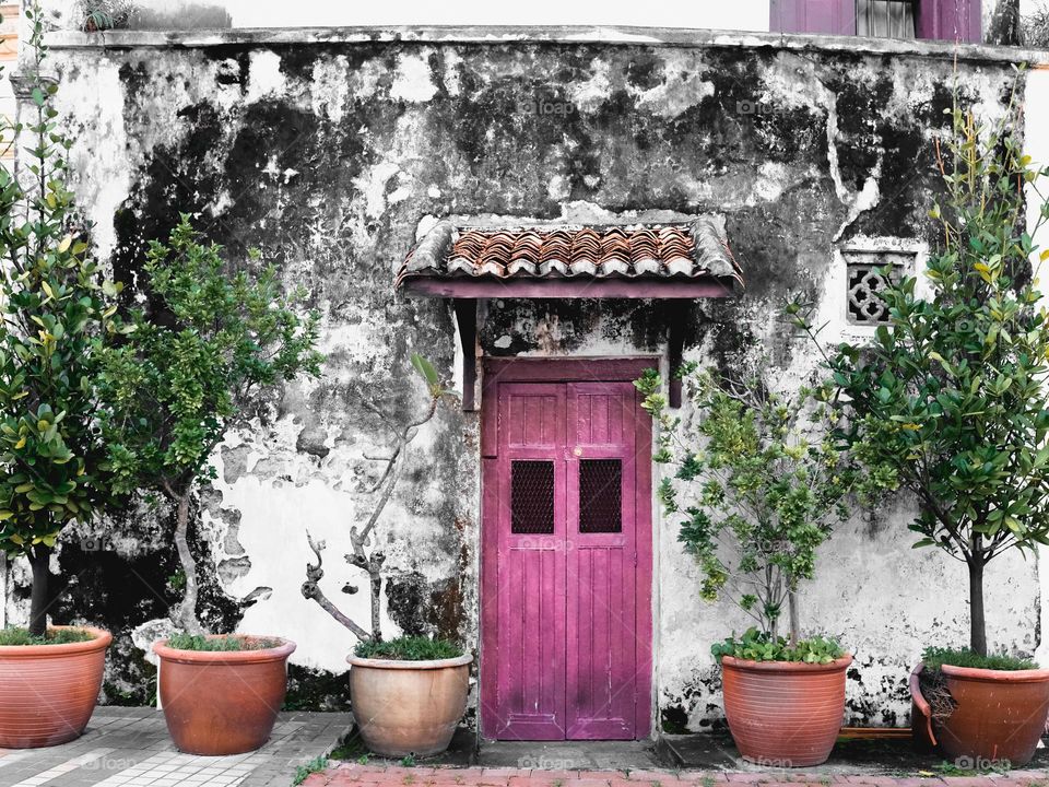 A rustic facade in Penang with pink door