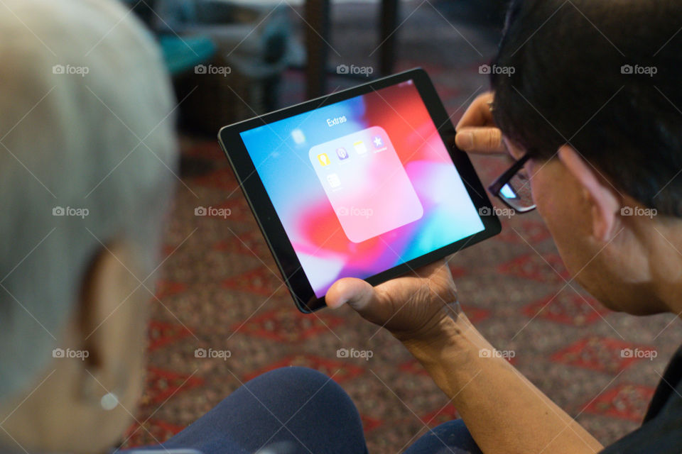 A man teaching an old lady on how to use an iPad 