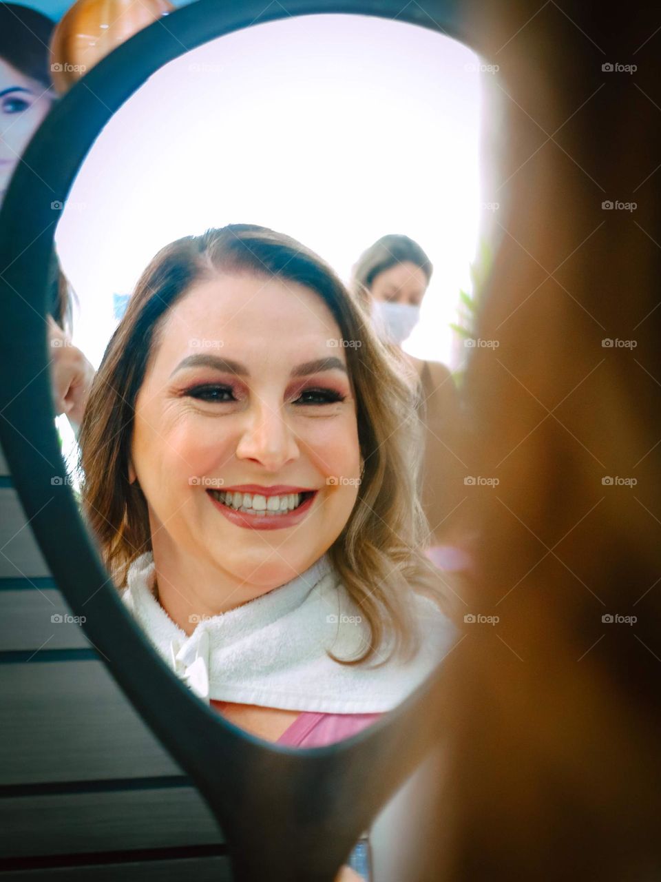 A Beautiful Bride getting her makeup and hair done to her wedding. She's looking at the results in the mirror.