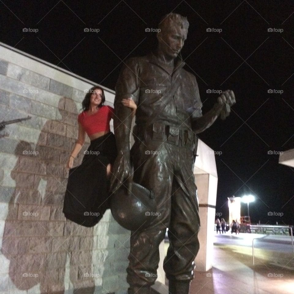 Happy young woman with statue of soldier at night