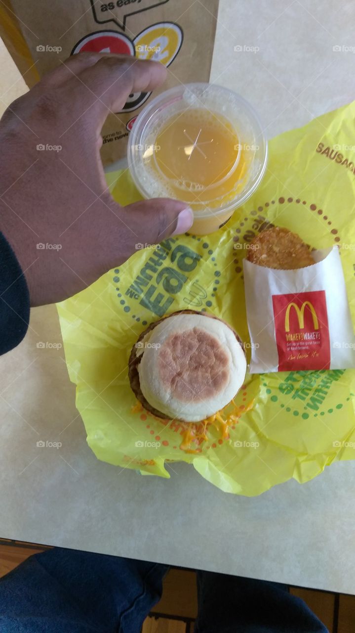 morning breakfast, McDonald's sausage egg McMuffin, hash brown, orange juice. Flat lay