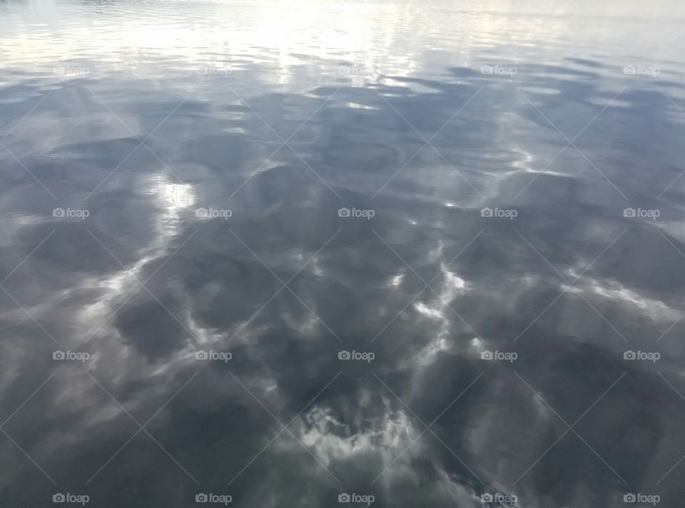 photo of reflection of clouds on the lake under grey skies