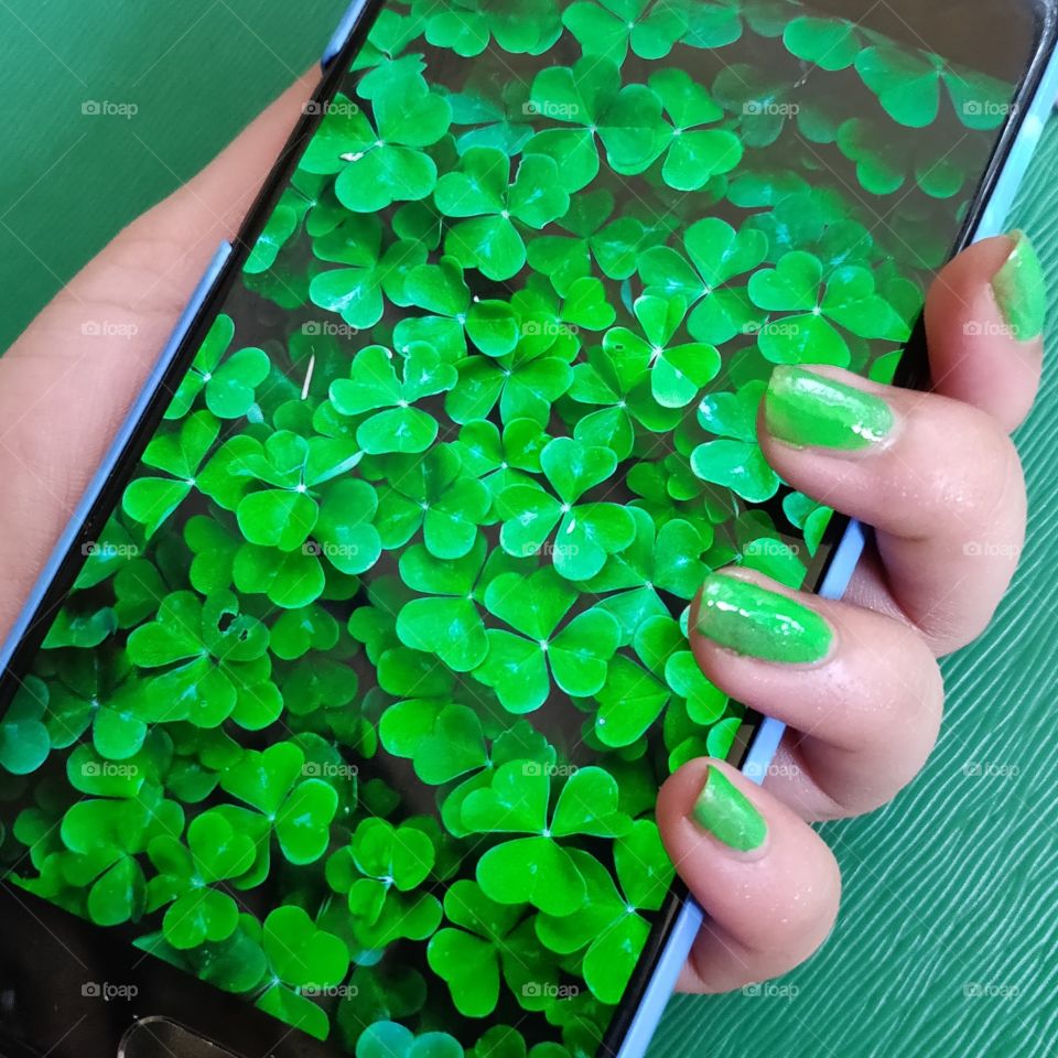 woman wearing green nail paint holding smartphone