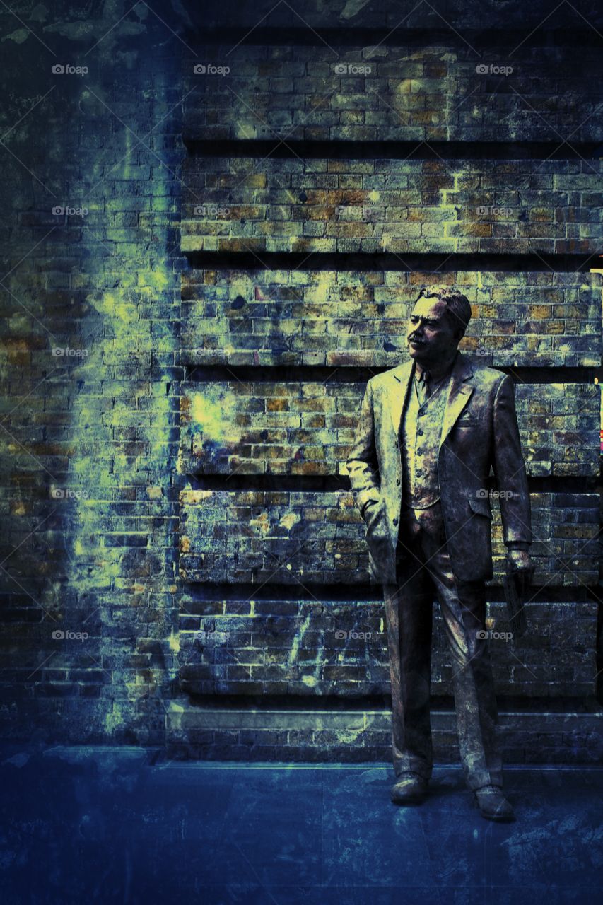 A stone statue of Sir Nigel Gresley, a famous, British railway engineer who built steam trains. Kings Cross Station in London, UK.