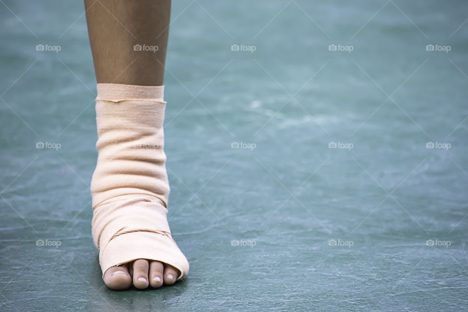 The  gauze bandages around the Ankle boy and leg swelling from inflammation On a green background.