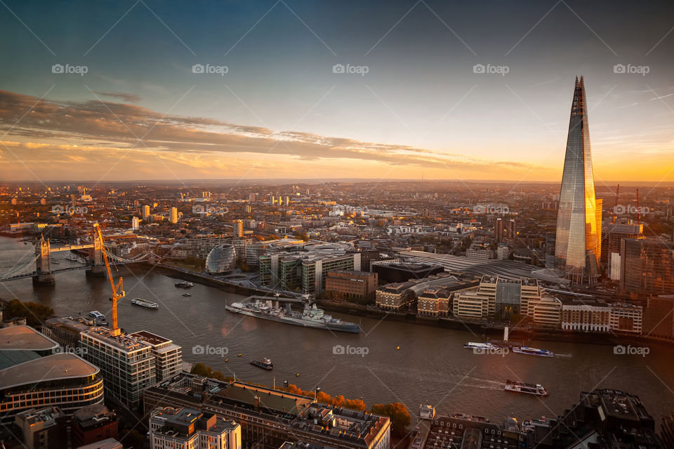 London. UK. Autumn sunset. From left: Tower Bridge, oval London's Parliament, warship HMS Belfast, skyscraper Shard second tallest in Europe.