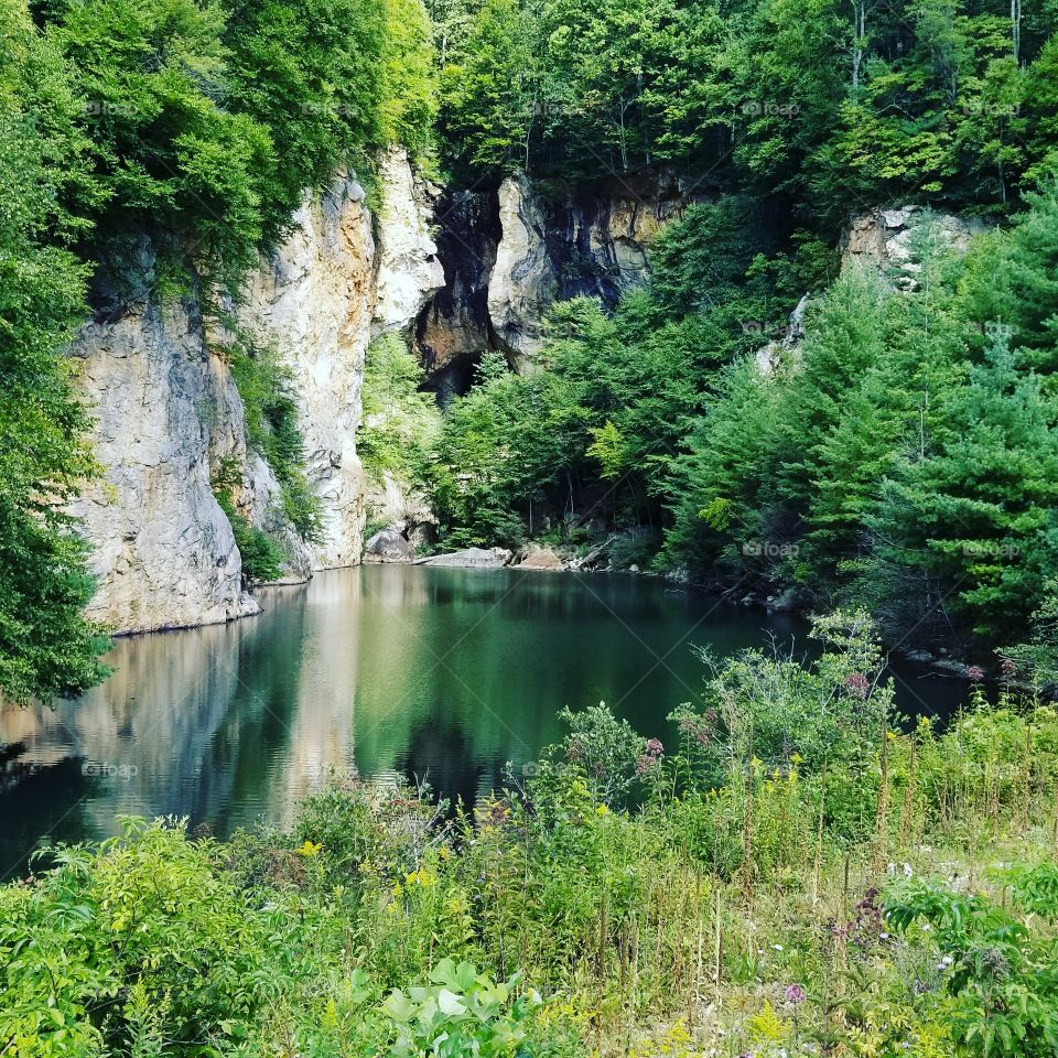 crystal clear waters sheltered by the cliffs of the Appalachian mountains. a secluded mountain swimming  hole.