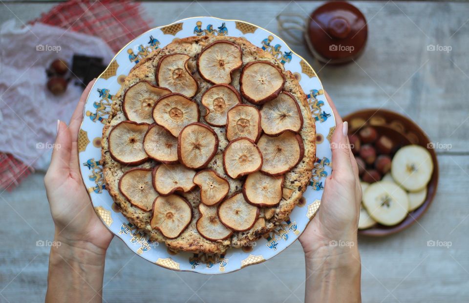 A woman is holding pear tart on plate
