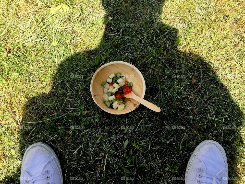 Wood Bowl of salad on the grass against man's silhouette.holiday piv shot.looking down