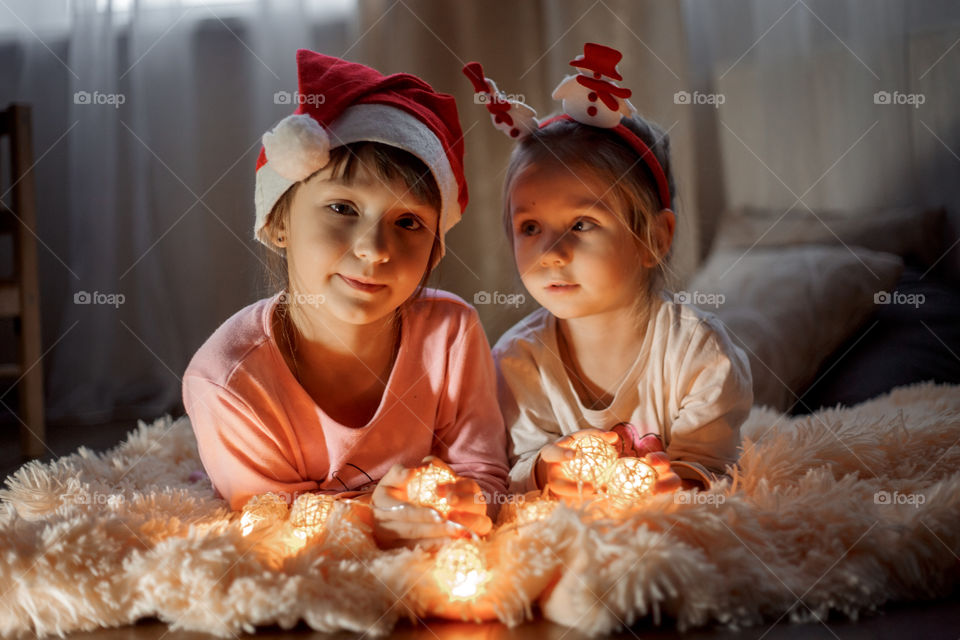 Little sisters reading a book at Christmas time 