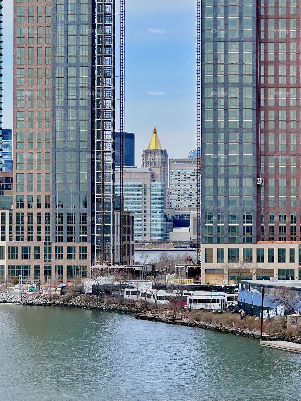 This is „Newtown Creek“ seen from the „Pulaski Bridge“ that connects „Greenpoint“, Brooklyn to LIC, Queens. Between two recently built LIC high rises we see the „New York Life Building“ in „Manhattan“. 2024. Hypnotic Productions