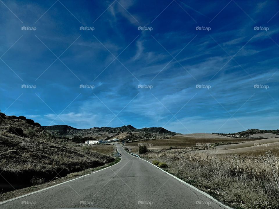 Lonely road against a cloudy blue sky.