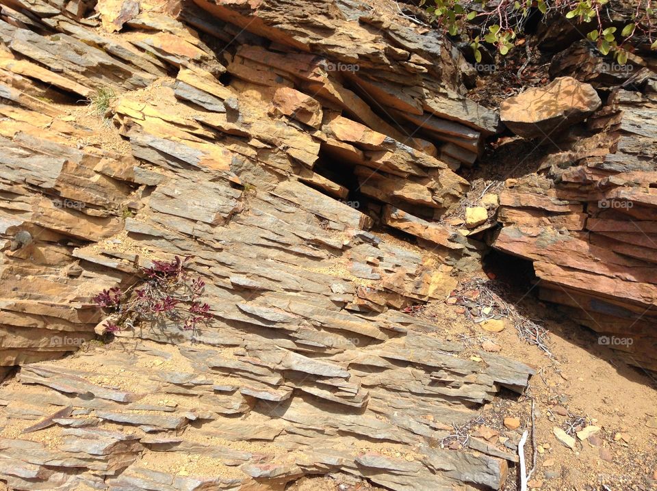 Rough layers of beautiful reddish brown rock on a hillside in Central Oregon on a sunny day. 