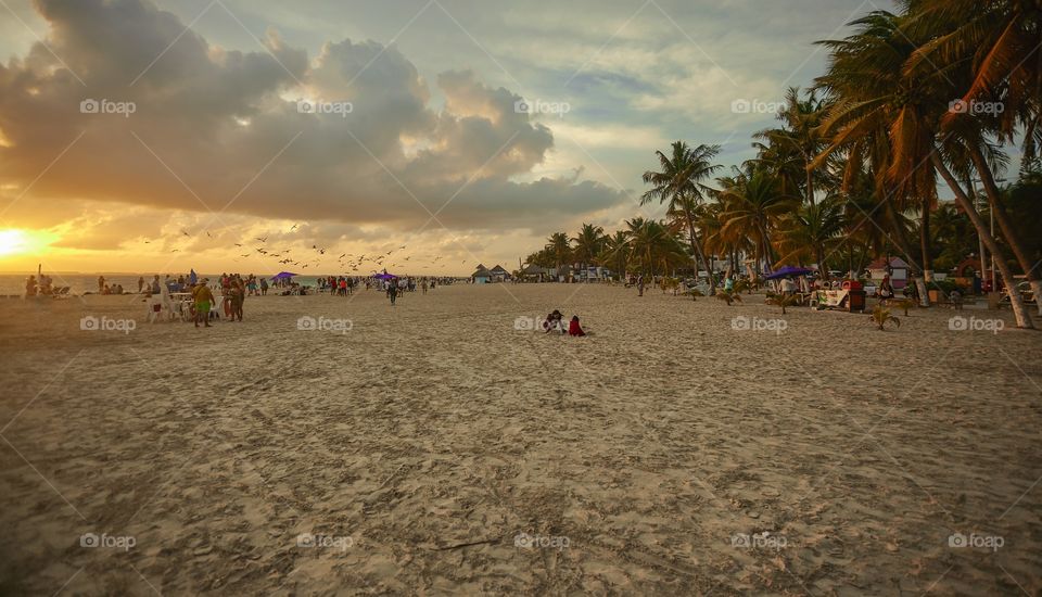 View of the beach of Isla Mujeres while you are populated by people who want to enjoy the spectacle of the sunset over the sea