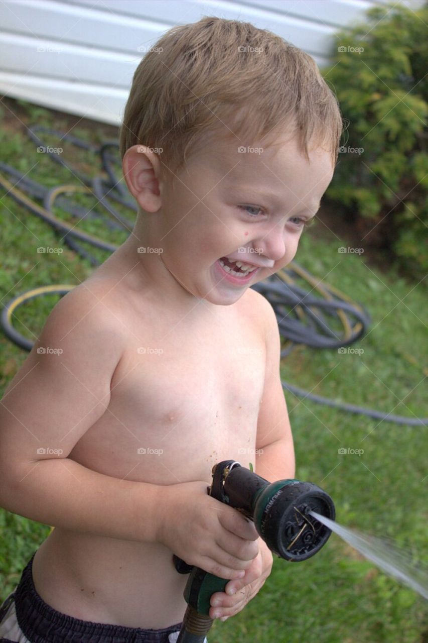 Portrait of a boy playing with hose in garden