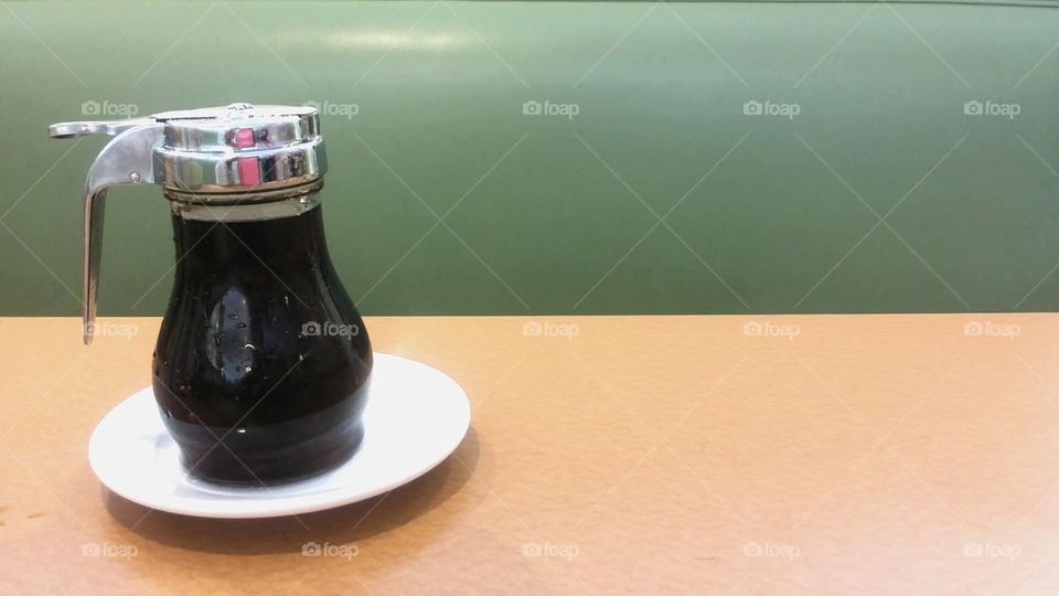 Syrup dispenser sitting on restaurant table