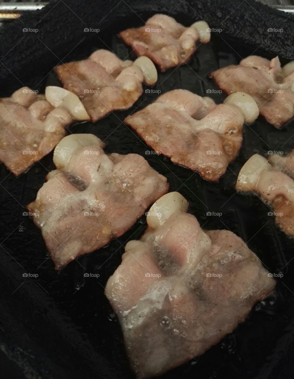 unhealthy bacon being grilled in a pan