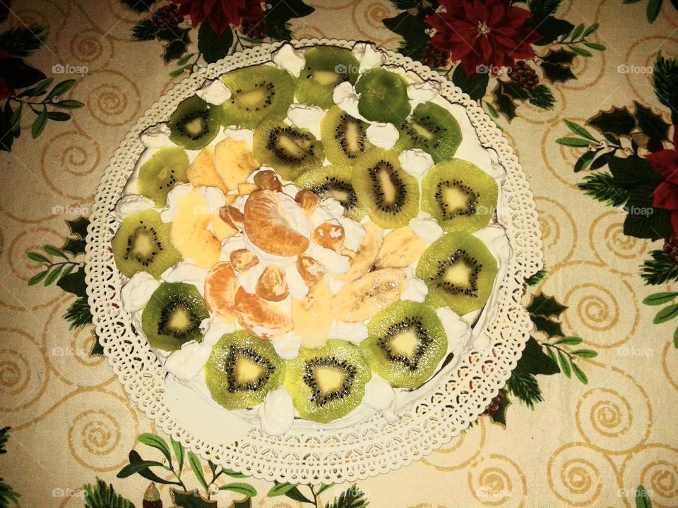 Cream cake covered with kiwi and mandarin wedges