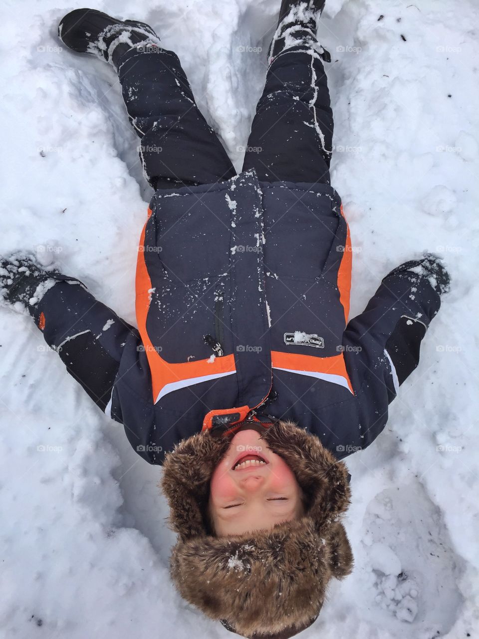 Little happy boy lying on snow